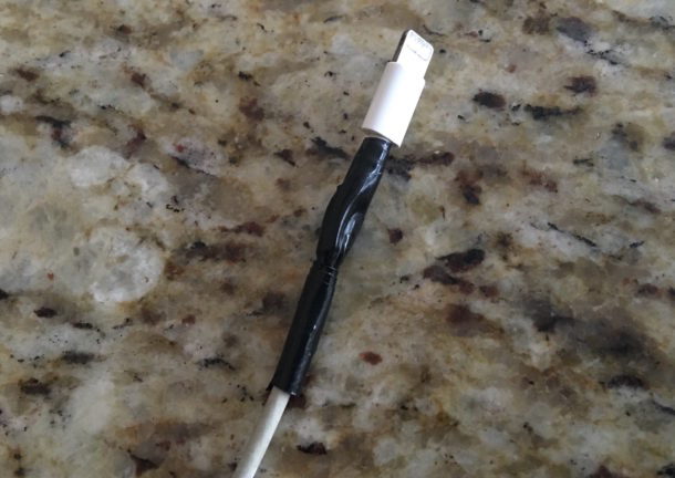 Зарезервированное поврежденное зарядное устройство iPhone, временно закрепленное электрической ленточкой